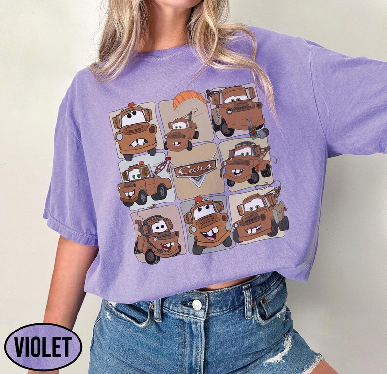 Może przedstawiać: Fioletowa koszulka z siatką brązowych kresk&oacute;wkowych w&oacute;zk&oacute;w holowniczych. Słowo "Cars" jest nadrukowane na wzorze. Koszulka ma kr&oacute;tkie rękawy i luźny kr&oacute;j. Słowo "VIOLET" jest wydrukowane po lewej stronie u dołu.