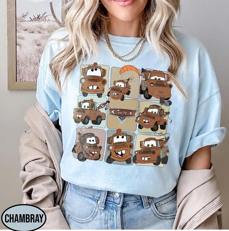 Może przedstawiać: Jasnoniebieska koszulka z siatką brązowych ilustracji samochod&oacute;w z kresk&oacute;wek. Na koszulce wydrukowano napis "Cars". Koszulka ma kr&oacute;tkie rękawy i okrągły dekolt.
