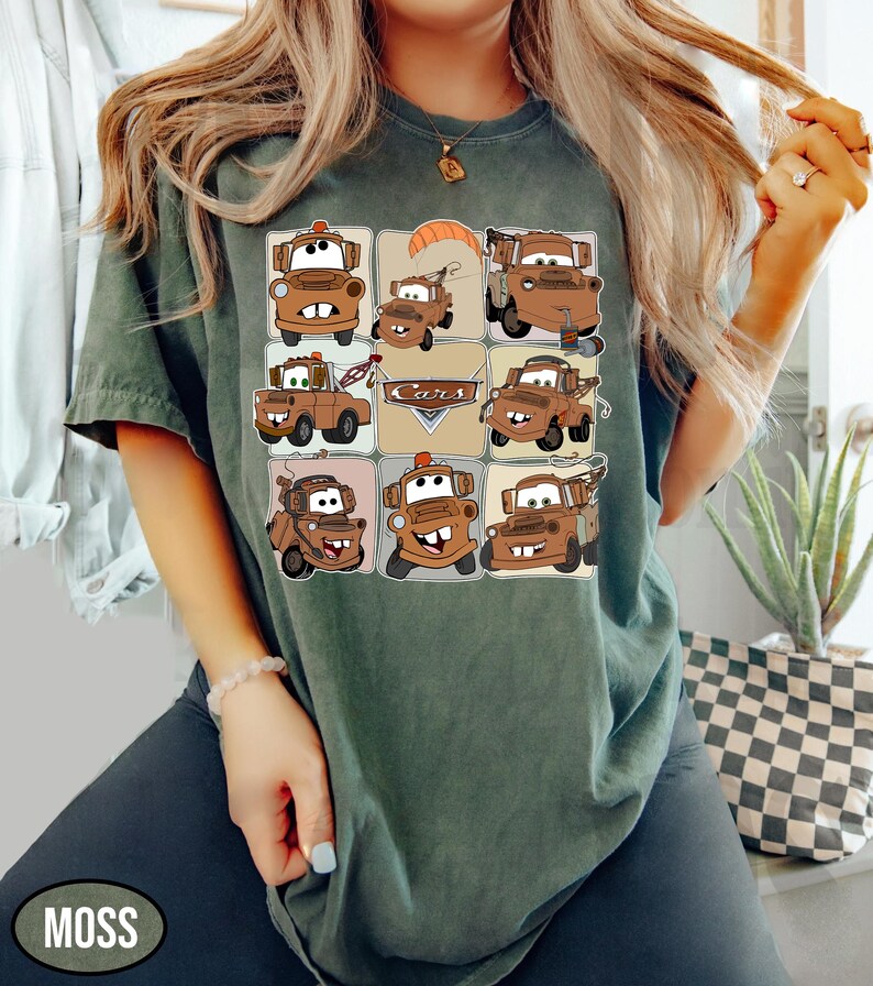 Może przedstawiać: Zielona koszulka w kolorze mchu z siatką kresk&oacute;wkowych wizerunk&oacute;w postaci Złomka z filmu Auta. Słowo "Cars" jest wydrukowane pośrodku. Koszulka jest noszona przez osobę.