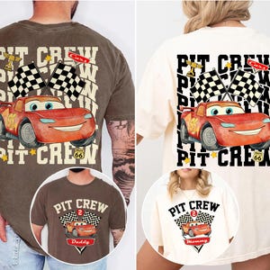 May include: Two t-shirts featuring a red cartoon race car with the text "PIT CREW". One shirt is brown and the other is cream. The design includes checkered flags, a trophy, and the number 95.