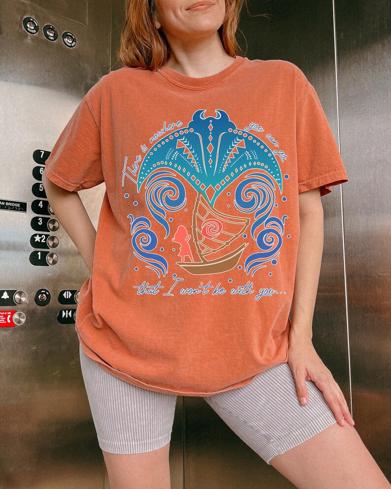 May include: Orange t-shirt with a graphic design featuring a boat, waves, and the text "There is nowhere you can go that I won't be with you..." The design is in shades of blue, orange, and brown. The shirt is worn with striped shorts.