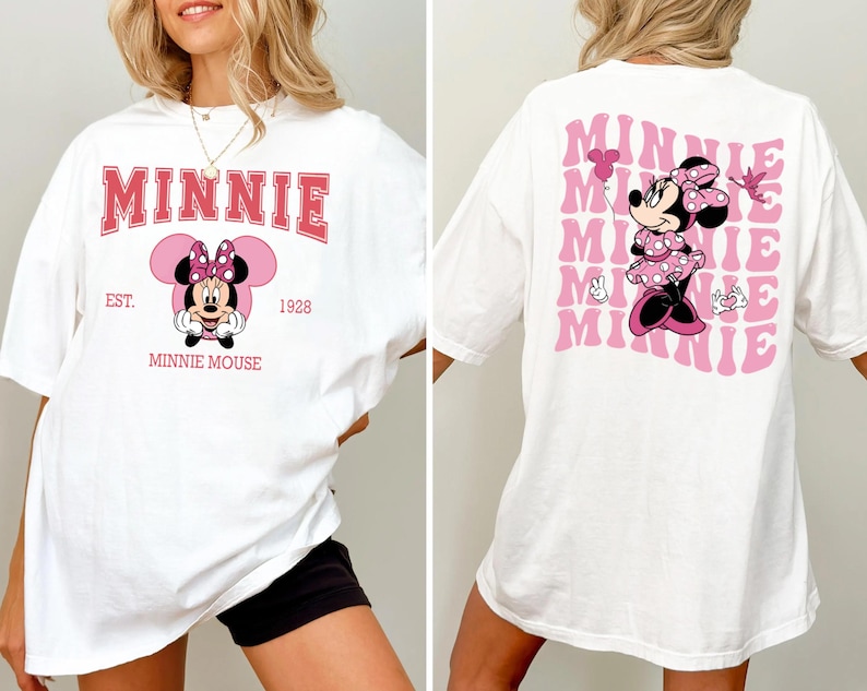 May include: White t-shirt featuring Minnie Mouse. The front design includes the word "MINNIE" in pink, with "EST. 1928" and "MINNIE MOUSE" below. The back displays a pink Minnie Mouse graphic with the word "MINNIE" repeated in a wavy pattern.
