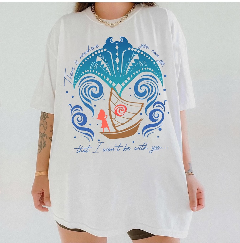 May include: White t-shirt featuring a colorful graphic design. The design includes a boat, waves, and a stylized palm tree in shades of blue, brown, and red. The text "There is nowhere you can go that I won't be with you..." is printed in blue.