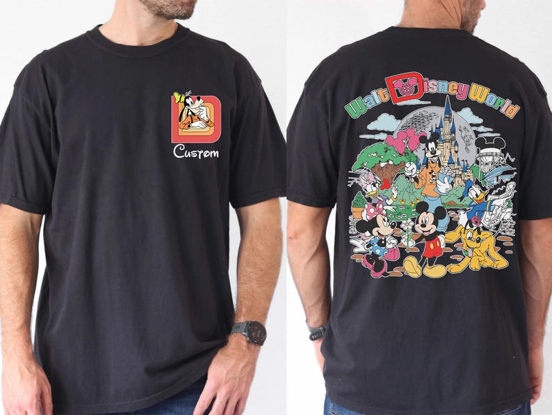 May include: Black t-shirt featuring a colorful Walt Disney World graphic on the back and a smaller Goofy design with the word "Custom" on the front. The shirt has a classic crew neck and short sleeves.