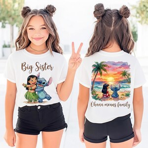 May include: White t-shirt with a "Big Sister" graphic featuring Lilo and Stitch. The back of the shirt displays a beach scene with palm trees, Lilo, and Stitch, and the text "Ohana means family". The shirt is paired with black shorts.