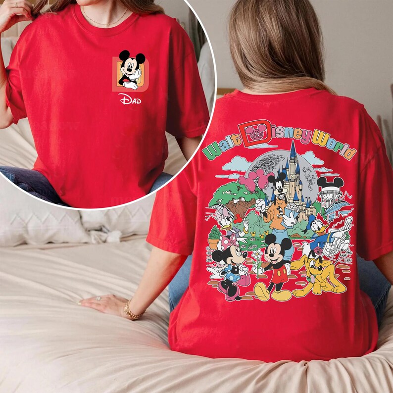 May include: Red t-shirt featuring a Mickey Mouse graphic on the front with the word "Dad" below. The back of the shirt displays a colorful Walt Disney World design with various cartoon characters and the park's logo.