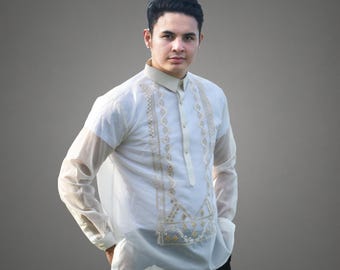 May include: A white long-sleeved shirt with gold embroidery. The shirt has a mandarin collar and a button-up front.