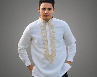 May include: White long-sleeved shirt with intricate gold embroidery down the front and around the collar. The shirt has a mandarin collar and buttoned cuffs. The person is wearing black pants. The shirt is a traditional formal wear.