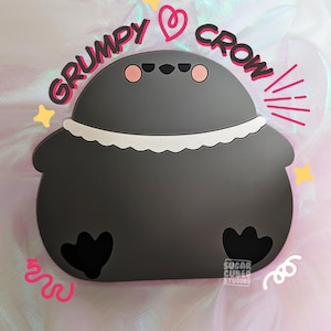 Op de afbeelding: Een donkergrijze cartoonkraai met een witte gefranjerde kraag en zwarte voeten. De tekst "GRUMPY CROW" staat boven de kraai, met hart- en steraccenten. Het Sugar Cubed Studios-logo is zichtbaar.