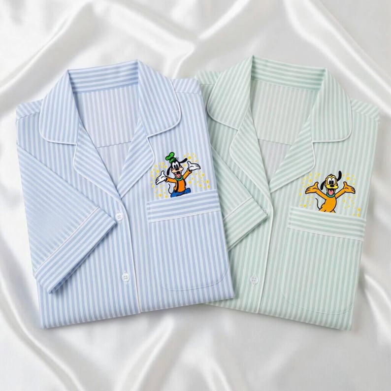 May include: Two pajama tops, one light blue and one mint green, both with vertical stripes. Each has a chest pocket and a cartoon character embroidered on it. The light blue top features Goofy, and the green top features Pluto.