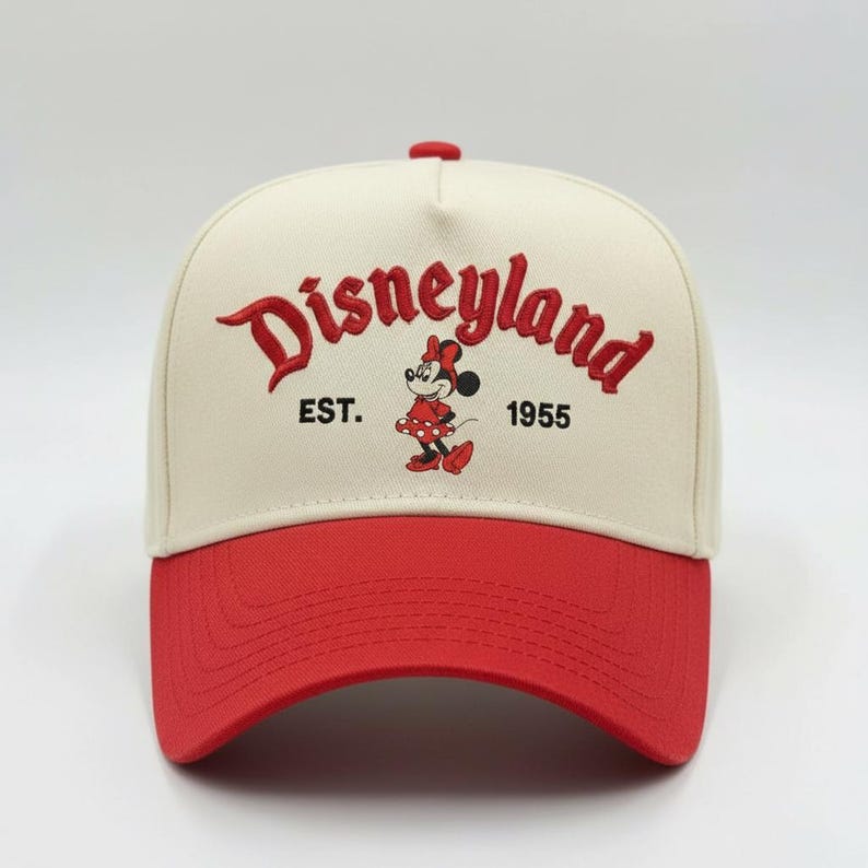 May include: A baseball cap with a cream-colored crown and a red brim. The front features the word "Disneyland" in red script, along with "EST. 1955" and a Minnie Mouse graphic. The cap has a red button on top.