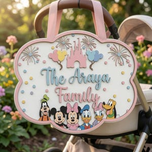 May include: A decorative wooden sign with a light pink border and white background featuring the text The Araya Family in blue and pink script. The sign includes a pink castle, colorful balloons, fireworks, and cartoon characters.