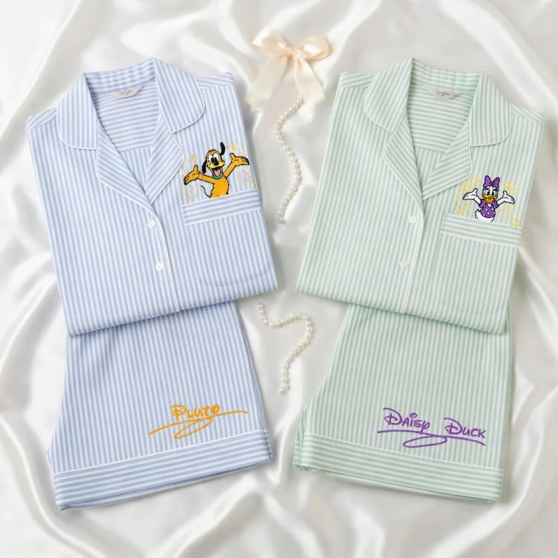 May include: Two sets of striped pajamas. One set is light blue with Pluto embroidered on the pocket and shorts. The other set is light green with Daisy Duck embroidered on the pocket and shorts. Both sets have white piping.
