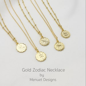 May include: Five gold necklaces with zodiac signs on the pendants. The signs are: Sagittarius, Taurus, Leo, Capricorn, and Pisces. The necklaces are on a white background. Gold Zodiac Necklace by Menuet Designs.