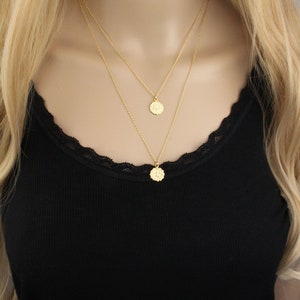 May include: A gold layered necklace with two delicate chains and two small round pendants.