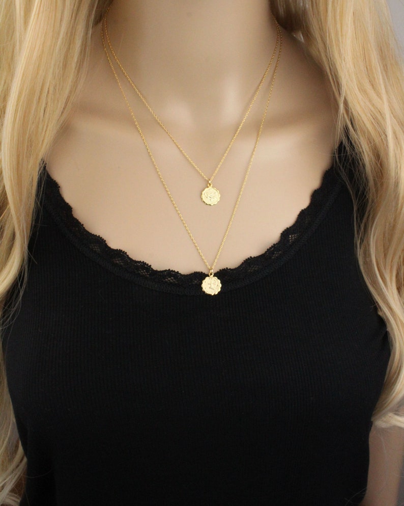 May include: A gold layered necklace with two delicate chains and two small round pendants.