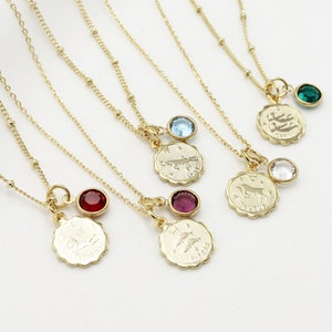 May include: Five gold necklaces with zodiac signs and colored gemstone charms. The signs are Pisces, Taurus, Gemini, Scorpio, and Sagittarius. The gemstones are red, blue, clear, green, and purple.