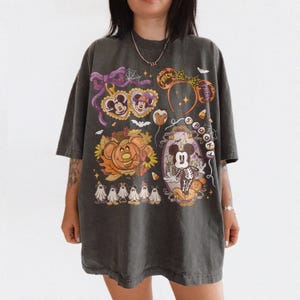 May include: A charcoal gray oversized t-shirt featuring a colorful Halloween-themed graphic print. The design includes Mickey Mouse ears, a pumpkin, ghosts, and the text "TRICK OR TREAT" and "SPOOKY" with various festive autumn and spooky icons.