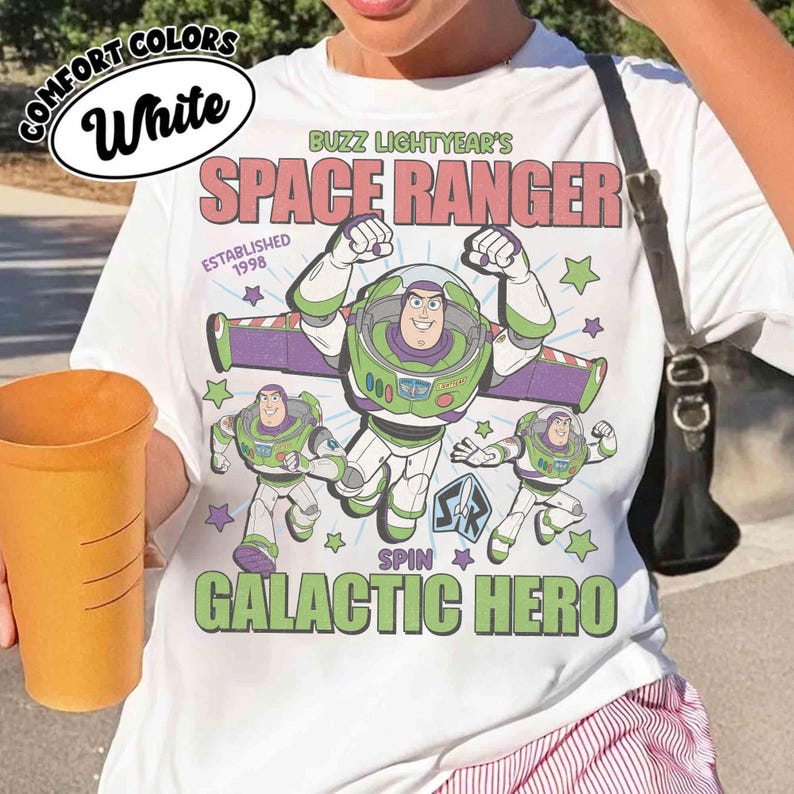 May include: White t-shirt featuring Buzz Lightyear's Space Ranger design. The graphic includes Buzz Lightyear in a green and white spacesuit, with the text "SPACE RANGER" and "GALACTIC HERO". The shirt also has the text "ESTABLISHED 1998".