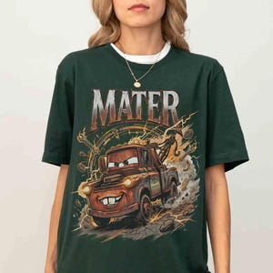 May include: Dark green t-shirt featuring a cartoon image of Mater from the movie Cars. The image includes the word "MATER" in a distressed font above the character. The graphic shows Mater with a smiling face, smoke, and lightning bolts.