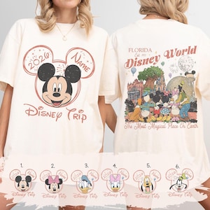 K&ouml;nnte beinhalten: Cremefarbenes T-Shirt mit einem Mickey Mouse-Motiv und dem Text "Disney Trip" und "2020". Auf der R&uuml;ckseite des Shirts ist eine farbenfrohe Disney World-Szene mit dem Text "Florida Disney World" abgebildet.