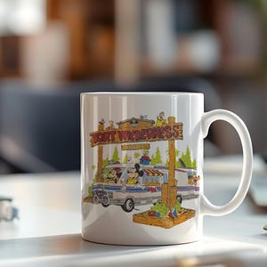 K&ouml;nnte beinhalten: Wei&szlig;er Keramikbecher mit einer farbenfrohen Illustration von Mickey und Minnie Mouse, die einen Van unter einem Holzschild mit der Aufschrift "FORT WILDERNESS RESORT" fahren. Der Becher hat einen gro&szlig;en Henkel und ist f&uuml;r hei&szlig;e oder kalte Getr&auml;nke geeignet.