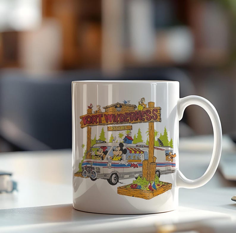 K&ouml;nnte beinhalten: Wei&szlig;er Keramikbecher mit einer farbenfrohen Illustration von Mickey und Minnie Mouse, die einen Van unter einem Holzschild mit der Aufschrift "FORT WILDERNESS RESORT" fahren. Der Becher hat einen gro&szlig;en Henkel und ist f&uuml;r hei&szlig;e oder kalte Getr&auml;nke geeignet.
