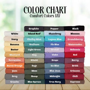 Op de afbeelding: Een kleurenkaart toont een verscheidenheid aan Comfort Colors 1717-stofstalen. De kaart bevat kleuren als wit, zwart, rood, blauw, groen en geel, met namen als "Graphite", "Chambray" en "Espresso".