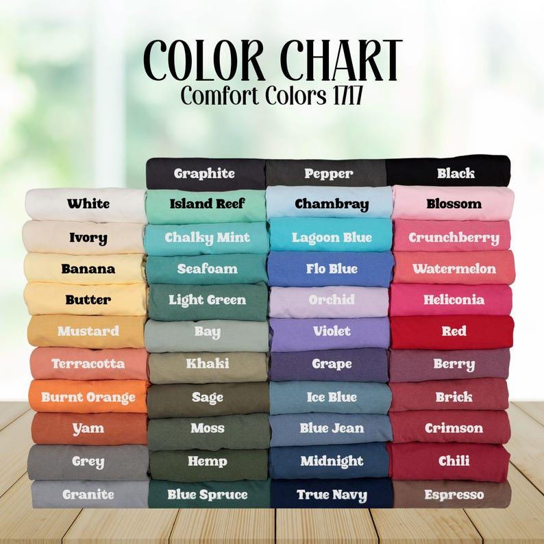 Op de afbeelding: Een kleurenkaart toont een verscheidenheid aan Comfort Colors 1717-stofstalen. De kaart bevat kleuren als wit, zwart, rood, blauw, groen en geel, met namen als "Graphite", "Chambray" en "Espresso".