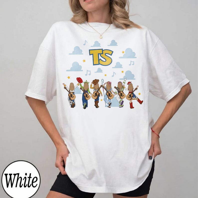 May include: A white short-sleeved t-shirt featuring a graphic print of six cartoon characters playing acoustic guitars. Above the characters are blue clouds, yellow stars, musical notes, and the large yellow and blue text TS.