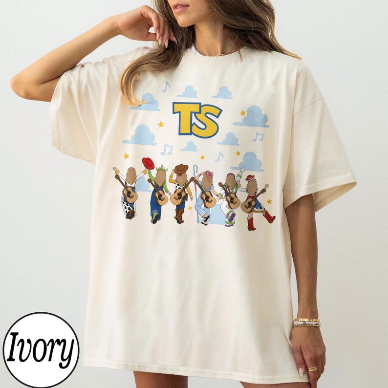 May include: An ivory short-sleeve t-shirt featuring a graphic print of six figures playing acoustic guitars. Above the figures, the letters TS are printed in yellow with a blue outline, surrounded by light blue clouds, stars, and musical notes.