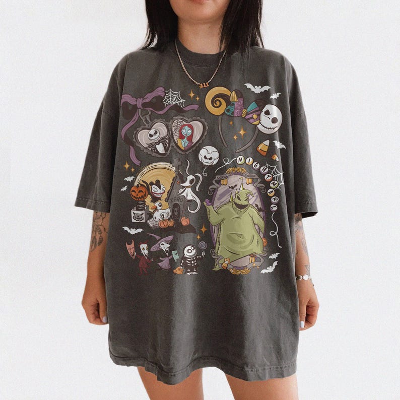 May include: A charcoal gray oversized t-shirt featuring a graphic print of characters and motifs from The Nightmare Before Christmas, including Jack Skellington, Sally, Oogie Boogie, Zero, and various Halloween-themed elements like bats and webs.