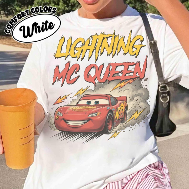 May include: White t-shirt featuring a graphic of Lightning McQueen from the Cars movie. The design includes the text "LIGHTNING MC QUEEN" in yellow and red, with a red race car and lightning bolts.