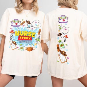 Pode incluir: Camiseta creme com um design de desenho animado colorido e ilustrações médicas. A frente mostra "NURSE STORY" com a frase "TO INFINITY AND BEYOND FOR OUR PATIENTS". A parte de trás tem ilustrações semelhantes.
