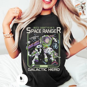 Puede incluir: Camiseta negra con un gr&aacute;fico de Buzz Lightyear de Toy Story. El dise&ntilde;o incluye el texto "Buzz Lightyear's Space Ranger" y "Galactic Hero". El gr&aacute;fico es en verde, morado, blanco y negro.