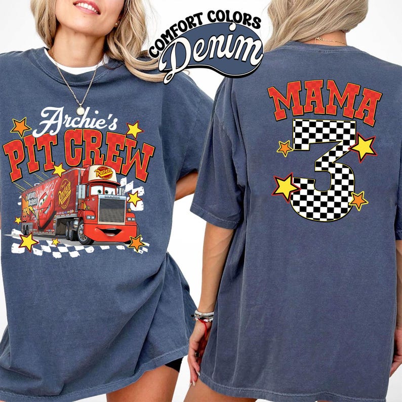 May include: A denim blue t-shirt featuring a graphic of a red truck with the text "Archie's Pit Crew" on the front. The back of the shirt displays the word "MAMA" and the number "3" in a checkered pattern, with star accents.