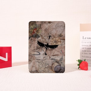 May include: A rectangular phone case featuring a map design with a black dragon silhouette and a person flying. The background is a sepia-toned map with various illustrations. The case has a glossy finish.