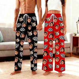 Könnte beinhalten: Schwarze und rote Schlafanzughosen mit einem sich wiederholenden Muster aus Gesichtern von Menschen und Haustieren. Die schwarzen Hosen haben einen weißen Kordelzug. Die roten Hosen haben einen roten Kordelzug. Die Schlafanzughosen sind aus weichem Material.
