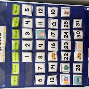 May include: A blue fabric calendar with pockets for each day of the month. The calendar has a title that says 'Apelila' and includes numbers 1 through 31. Each pocket has a different image, such as a school bus, a globe, and a birthday cake.