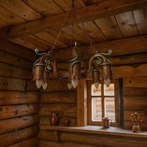 May include: A rustic, wrought-iron chandelier with six lights. The fixture has a brown finish with green accents and is suspended from a chain. The lampshades are shaped like flower buds with frosted glass. The chandelier hangs in a room with wooden walls and ceiling.