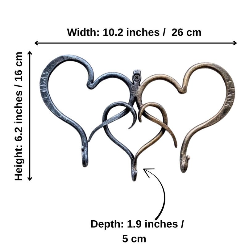 May include: A metal wall hook with a heart design. The hook is 10.2 inches wide, 6.2 inches high, and 1.9 inches deep. The design features three intertwined hearts in shades of gray and bronze. The names "LUCAS" and "LINDA" are inscribed on the hearts.