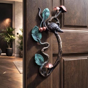 Könnte beinhalten: Ein dekorativer Türgriff mit einem skurrilen Design. Der Griff zeigt eine stilisierte Maus, Pilze, Blätter und Kirschen in Bronze-, Kupfer- und Türkistönen. Der Griff ist an einer dunkelbraunen Holztür befestigt.