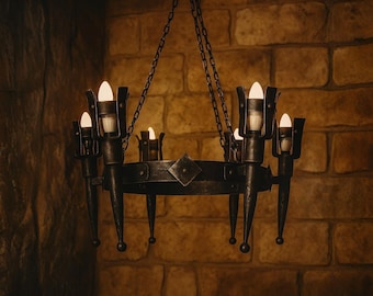 May include: A wrought iron chandelier with eight candle-shaped lights. The fixture is suspended by chains and features a circular design with decorative elements. The chandelier is against a brick wall.