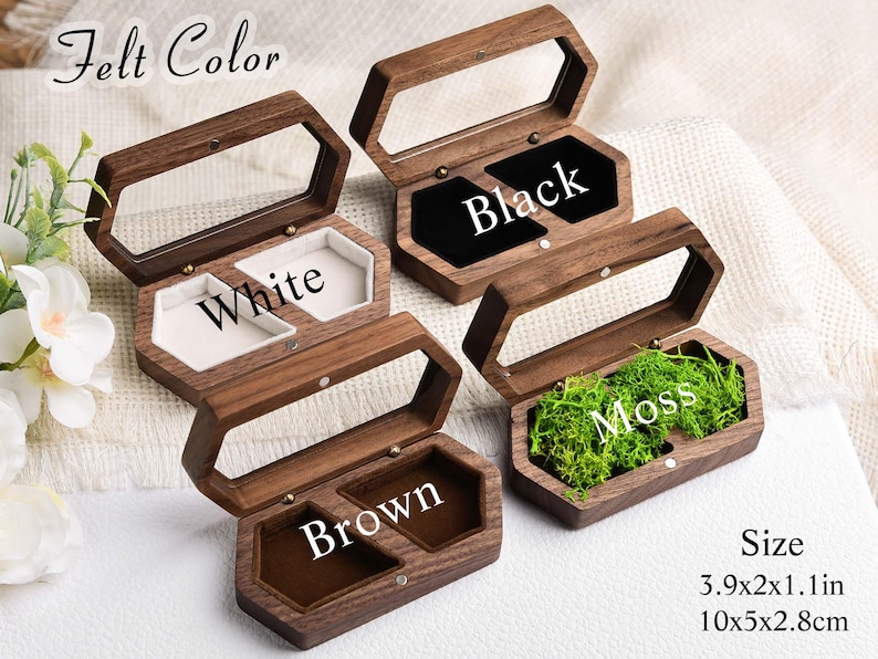 Op de afbeelding: Houten sieradenkistjes met doorzichtige deksels, verkrijgbaar met zwarte, witte, bruine en met mos gevulde interieurs. De kistjes zijn zeshoekig en meten 10 x 5 x 2,8 cm.