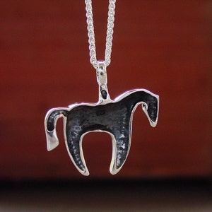 May include: Silver horse pendant necklace. The horse is facing right and has a detailed design. The necklace is on a silver chain.