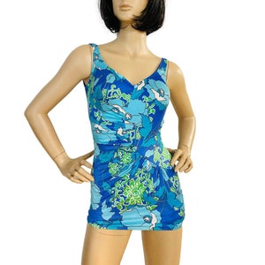 May include: A blue and green floral print swimsuit with a scoop neck and thin straps. The swimsuit has a fitted bodice and a short skirt.