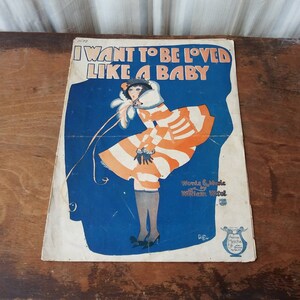 May include: Vintage sheet music cover featuring a woman in a striped dress with a white fur collar. The title of the song is "I Want to Be Loved Like a Baby" with the words and music credited to William Witti.