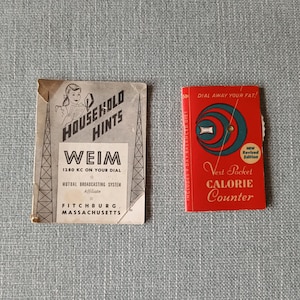 Op de afbeelding: Een rood-wit pamflet met de tekst "Household Hints" en "Weim 1280 KC on your dial" en een rood boekje met de tekst "Dial Away Your Fat!" en "Vest Pocket Calorie Counter".