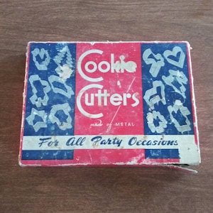May include: Vintage cookie cutters in a blue and red box with the text "Cookie Cutters" and "For All Party Occasions".