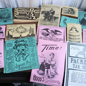 May include: A selection of antique advertising leaflets and booklets, featuring vibrant graphics and text. The items, in shades of pink, blue, and yellow, showcase illustrations and text promoting various products, typical of the era.